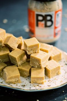 a plate full of peanut butter fudges next to a jar of peanut butter