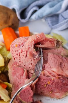 a fork is stuck into corned beef with carrots and lettuce on the side