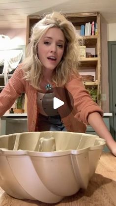 a woman standing in front of a large bowl on top of a wooden countertop