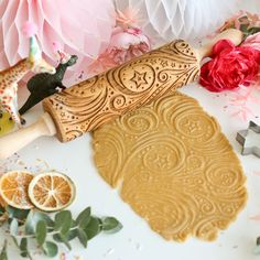 a cake knife sitting on top of a cutting board next to flowers and decorations with paper pom poms