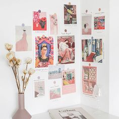 a vase filled with flowers sitting next to a wall covered in pictures and art pieces