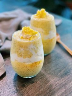 two glasses filled with dessert sitting on top of a wooden table