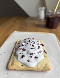 a pastry with white icing and crumbles on it sitting on a napkin