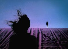 a person standing on top of a snow covered slope with their hair blowing in the wind