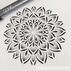 a drawing of a flower with black and white ink on paper next to a marker pen