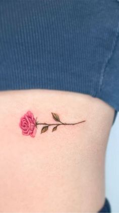 a woman's stomach with a small rose tattoo on the back of her belly