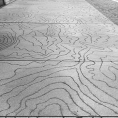 a bench sitting on the side of a road next to a sidewalk with lines drawn on it