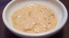 a white bowl filled with sauce on top of a wooden table