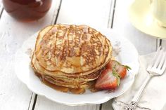 pancakes with syrup and strawberries on a white plate