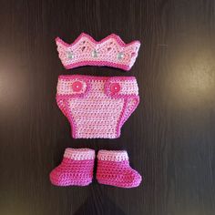 a crocheted baby outfit and booties with a tiara on the top