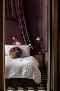 a bed sitting in a bedroom next to a purple wall