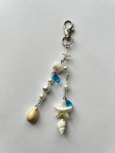 a key chain with seashells and pearls hanging from it's side on a white surface