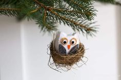 an owl ornament hanging from a pine tree