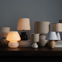 many different lamps on a table with one light turned on and the other turned off