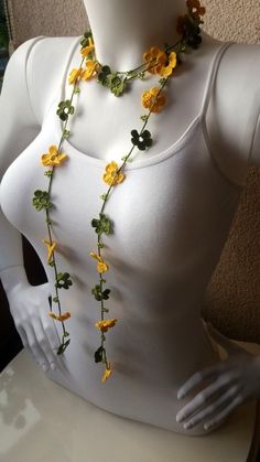 a white mannequin with yellow flowers and green leaves on it's neck