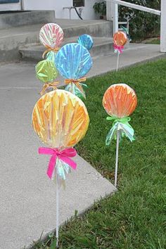 some colorful candy lollipops sitting in the grass on top of a sidewalk