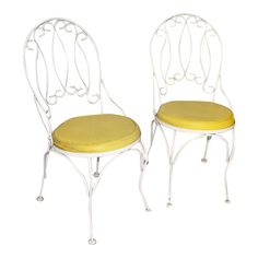 two white metal chairs with yellow cushions on each one and the other side facing opposite directions