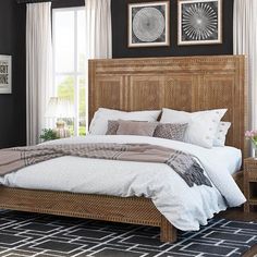 a bedroom with black walls, white bedding and wooden headboard in the middle