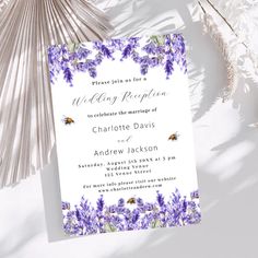 a wedding reception card with purple flowers on it and a fan next to the cards