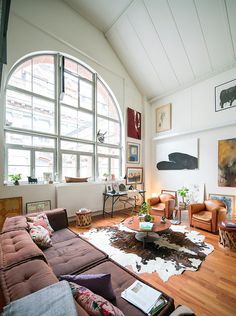 a living room filled with lots of furniture and large round window above the couches