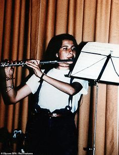 a woman playing the flute in front of a curtain