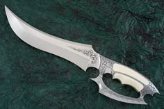 a knife that is sitting on top of a green tablecloth with black and white designs