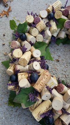 a wreath made out of wine corks and purple flowers on the ground next to leaves