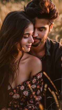 a man and woman standing next to each other in tall grass with their eyes closed