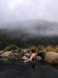 a woman sitting in a hot tub surrounded by rocks