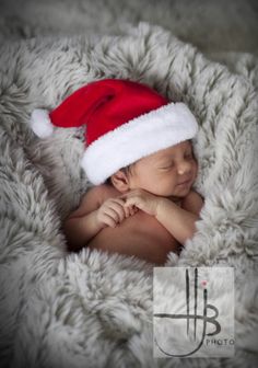 a baby wearing a santa hat on top of a blanket