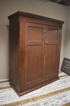 an old wooden cabinet sitting on top of a hard wood floor next to a sign