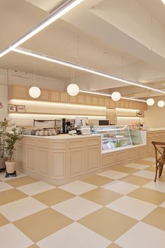 an empty restaurant with checkered flooring and white lights hanging from the ceiling above it