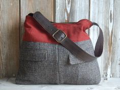 a gray and red purse sitting on top of a wooden table next to a wall