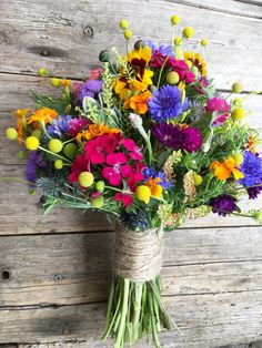 a bouquet of colorful flowers tied to a wooden wall