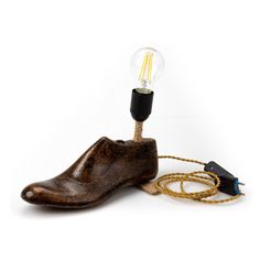 a light bulb sitting on top of a wooden shoe with a cord attached to it