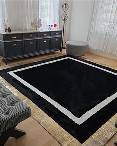 a living room with a large black rug on the floor and a chair in front of it