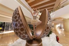 a ballerina is standing on top of an egg in the middle of a shopping mall