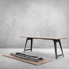 a wooden table sitting on top of a floor next to a piece of metal equipment