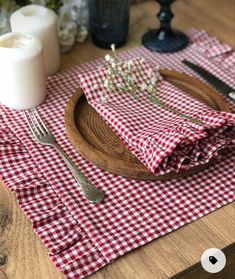 a red and white checkered table cloth on a wooden plate with fork, knife and candle