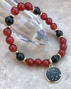 Leo Zodiac Astrological Bracelet Carnelian & Black Tourmaline 8mm Gemstone Beads with Gold Plated Spacers and Zodiac CharmCarnelian, a stone of courage and creativity, is also known to restore vitality. Carnelian is known to bring good luck, success and manifestation of ones desires.Black Tourmaline is a premier stone of protection by creating a psychic shield around a persons energy field which repels and blocks negative energies, thought forms, destructive forces and psychic attack. Black Tour Leo Crystal Bracelet, Psychic Attack, Zodiac Bracelet, Leo Zodiac, Energy Field, Black Tourmaline, Gemstone Bracelet, Round Beads, Tourmaline