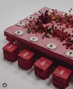 the table is set with red napkins and plates on it, all covered in flowers