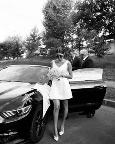 a woman in a dress standing next to a car