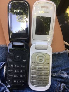 two cell phones sitting next to each other on someone's stomach in front of trees