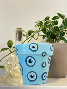 two vases sitting on top of a white shelf next to a potted plant