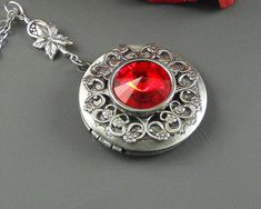 Ruby red Victorian Steampunk Locket is 30 inches long. Feminine antique silver locket is decorated with Victorian style antique silver floral frame. I have set Swarovski red Crystal stone in the middle of locket which is set in silver setting. Pendant is hanging from a antique silver leafy rosary link. Necklace is finished with antique silver chain and antique silver royal toggle clasp. Locket is 32 mm in size. It opens and has room for two photos inside. Please note: I DO NOT DO ENGRAVING OR IN Red Victorian Necklace For Anniversary, Antique Red Necklace For Wedding, Red Locket Necklace For Formal Occasions, Red Locket Jewelry For Valentine's Day, Victorian Red Jewelry For Wedding, Ornate Red Wedding Necklaces, Victorian Red Wedding Jewelry, Red Round Locket Jewelry, Vintage Red Round Pendant Jewelry