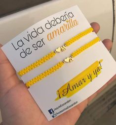 two yellow bracelets with hearts on them are being held in front of a card