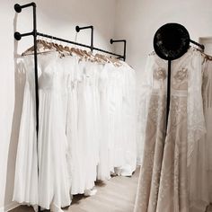 there are many dresses on display in the store, and one is white with black trim