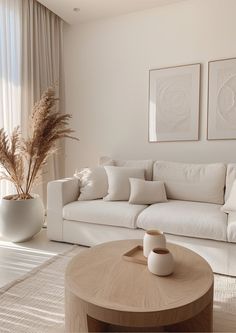 a living room filled with white furniture next to a tall vase full of flowers and plants