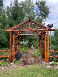 a wooden gazebo in the middle of a forest