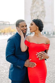 a woman in a red dress and a man in a blue suit stand next to each other